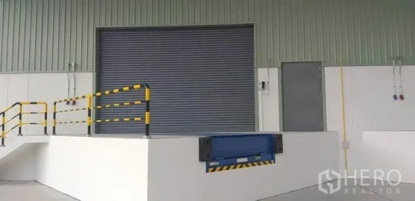 Factory for rent in Mueang Rayong, Rayong - Loading dock featuring a mechanical dock leveler, safety railings and a closed metal roller shutter.
