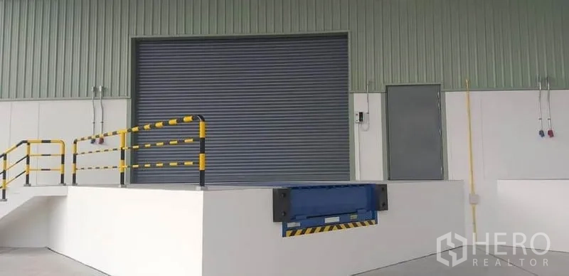 Factory for rent in Mueang Rayong, Rayong - Loading dock featuring a mechanical dock leveler, safety railings and a closed metal roller shutter.