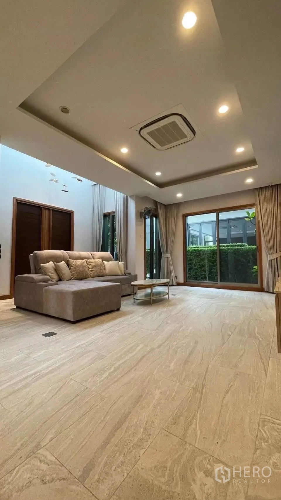 บ้านเดี่ยว for rent in Prawet, Bangkok - ห้องนั่งเล่นมีโซฟารูปตัวแอล โต๊ะกลาง และประตูกระจกบานเลื่อนเปิดสู่สวนแนวรั้ว