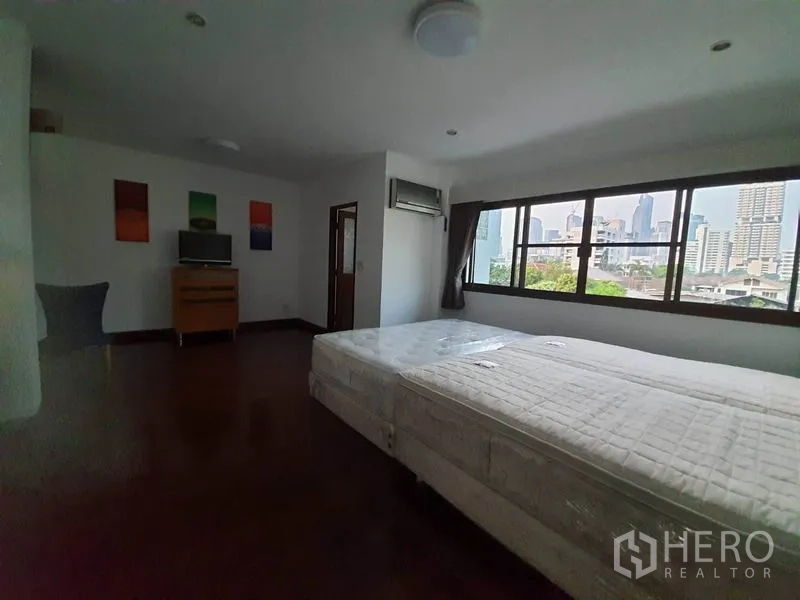 联排别墅 出租在Khlong Toei, Bangkok - 大卧室，双床垫与横向大窗，可见城市景观