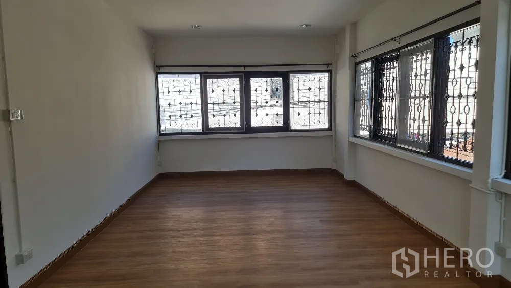 独栋房屋 for rent in Lat Phrao, Bangkok - 采光充足的卧室，木地板与带防护格栅的窗户。
