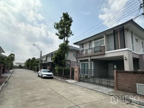 独立式住宅 出售在Sai Mai, Bangkok - 宁静社区街景，可见房屋与停放的汽车。