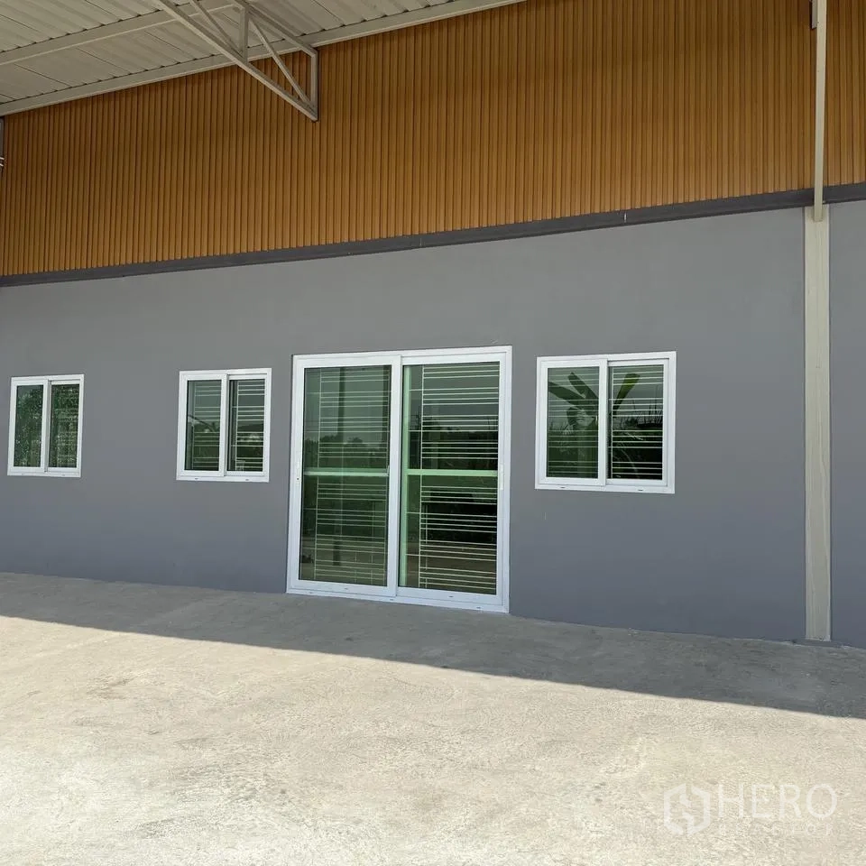 Warehouse for rent or sale in Khlong Luang, Pathum Thani - Front facade with sliding glass door and windows opening to a loading apron.