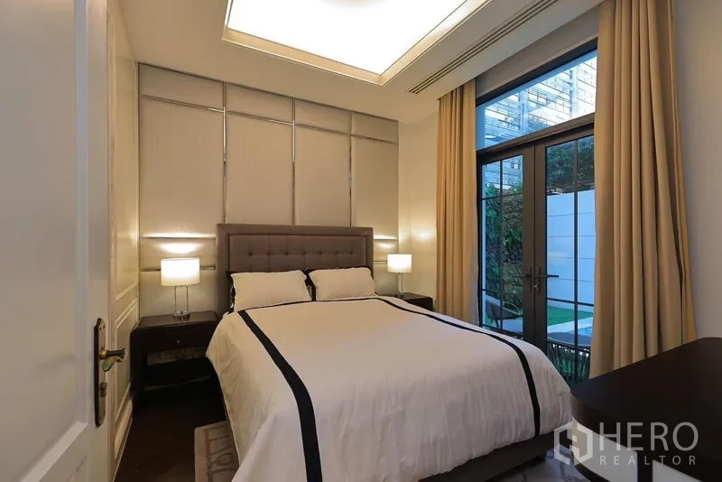 Detached House for rent or sale in Watthana, Bangkok - Guest bedroom with garden access through glass doors and recessed ceiling lighting.