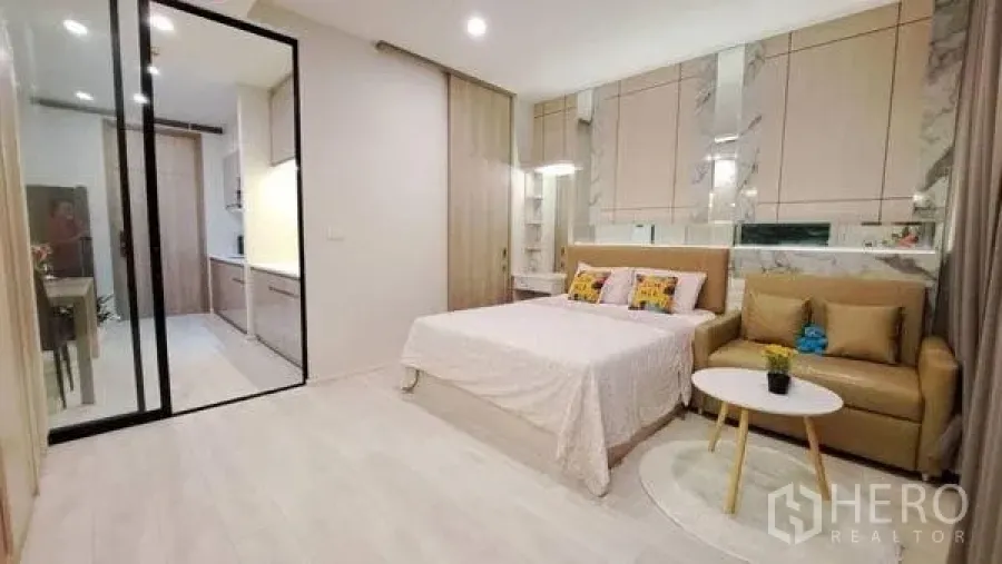 Condominium for rent or sale in Pathum Wan, Bangkok - Cozy sleeping area with bed, sofa and a mirrored headboard wall.