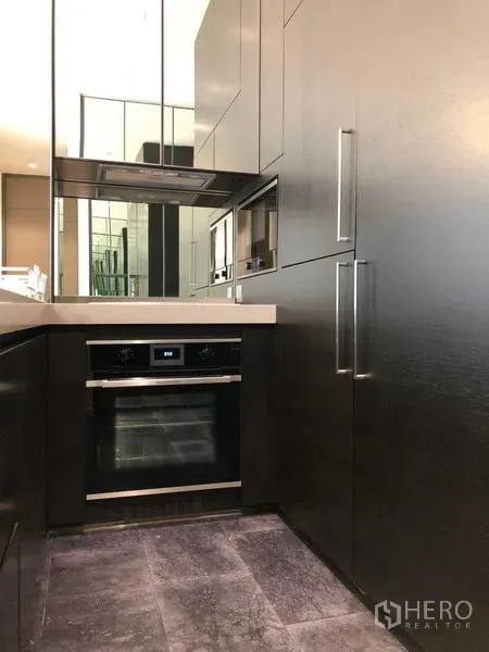 Condominium for rent - Sleek galley kitchen with black cabinetry, built-in oven and mirrored backsplash.