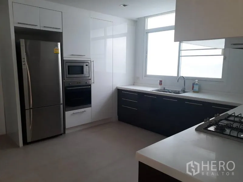 Detached House for rent in Watthana, Bangkok - Contemporary kitchen with stainless fridge, built-in oven and microwave, gas hob and white countertops