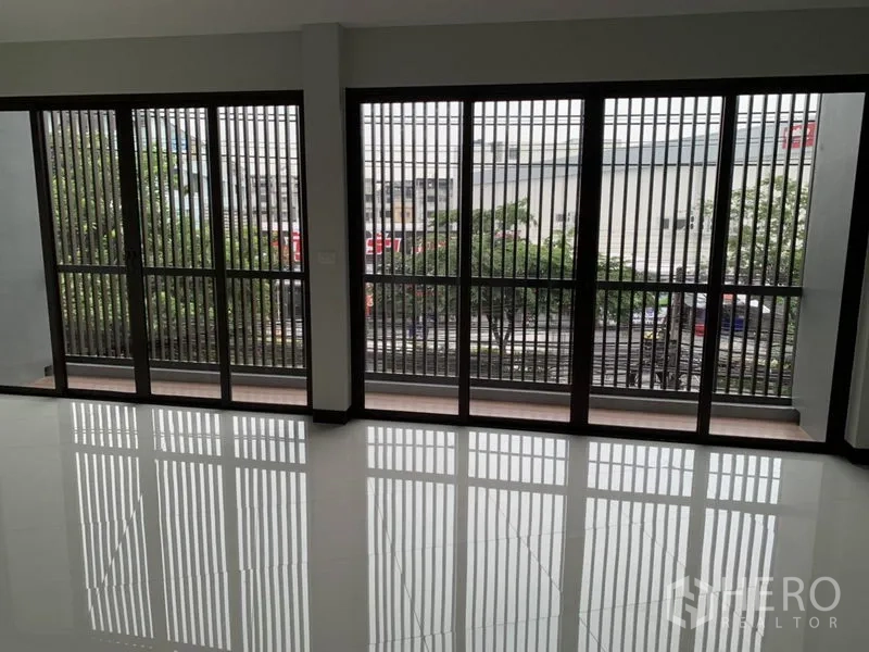 Shophouse for rent in Suan Luang, Bangkok - Floor-to-ceiling sliding glass windows with metal grilles overlooking the street.