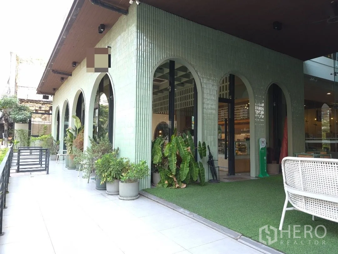 Retail Space for rent in Watthana, Bangkok - Green-tiled retail exterior with arched glass windows, terrace walkway, and potted plants.