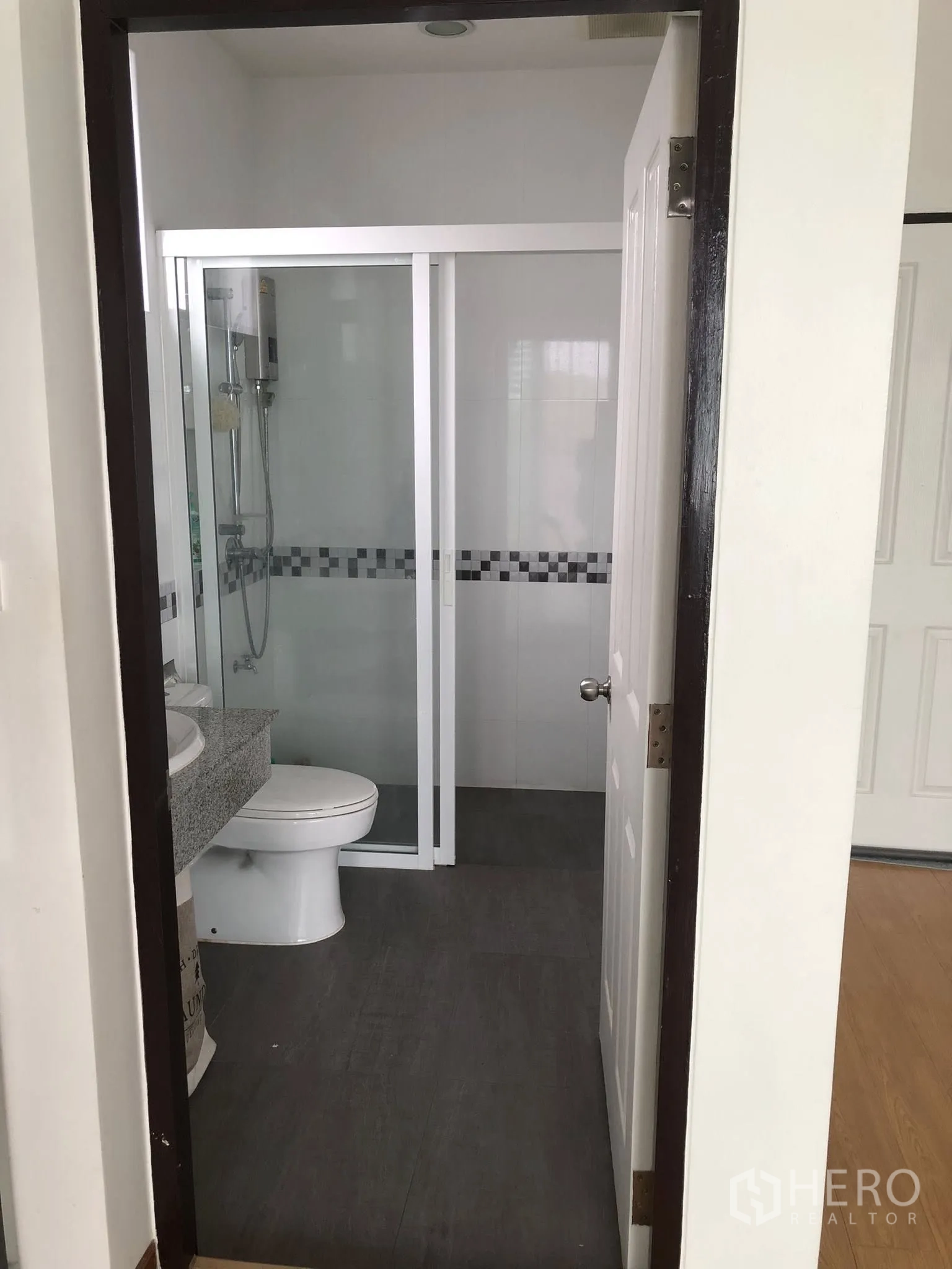Townhouse for sale in Phra Khanong, Bangkok - Modern bathroom with glass-enclosed shower, granite vanity and gray floor tiles.