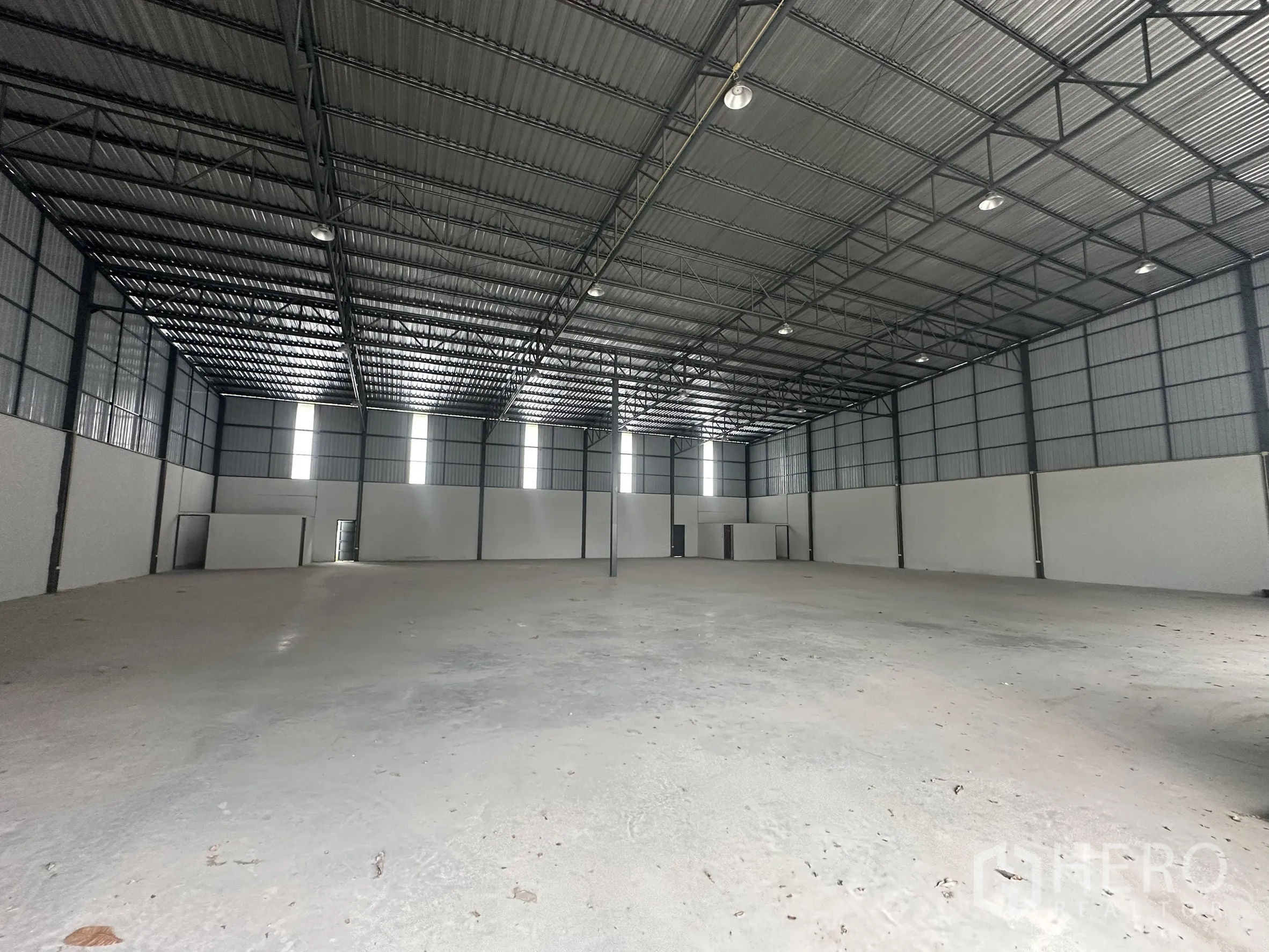 Warehouse for rent in Lam Luk Ka, Pathum Thani - Deep view of the warehouse with skylights, white internal walls and smooth concrete slab.
