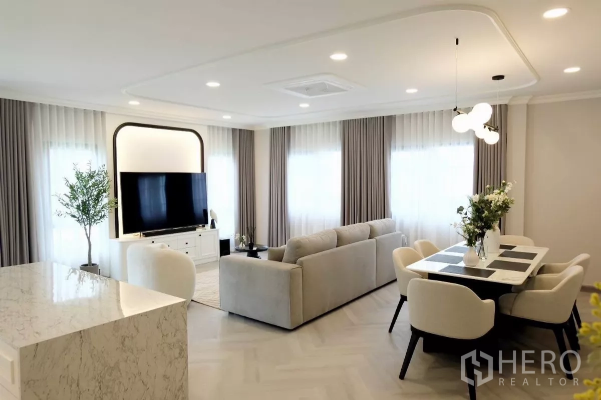 Detached House for sale in Bang Phli, Samut Prakan - Bright open-plan living and dining area with marble island, large sofa, feature TV wall and full-height curtained windows