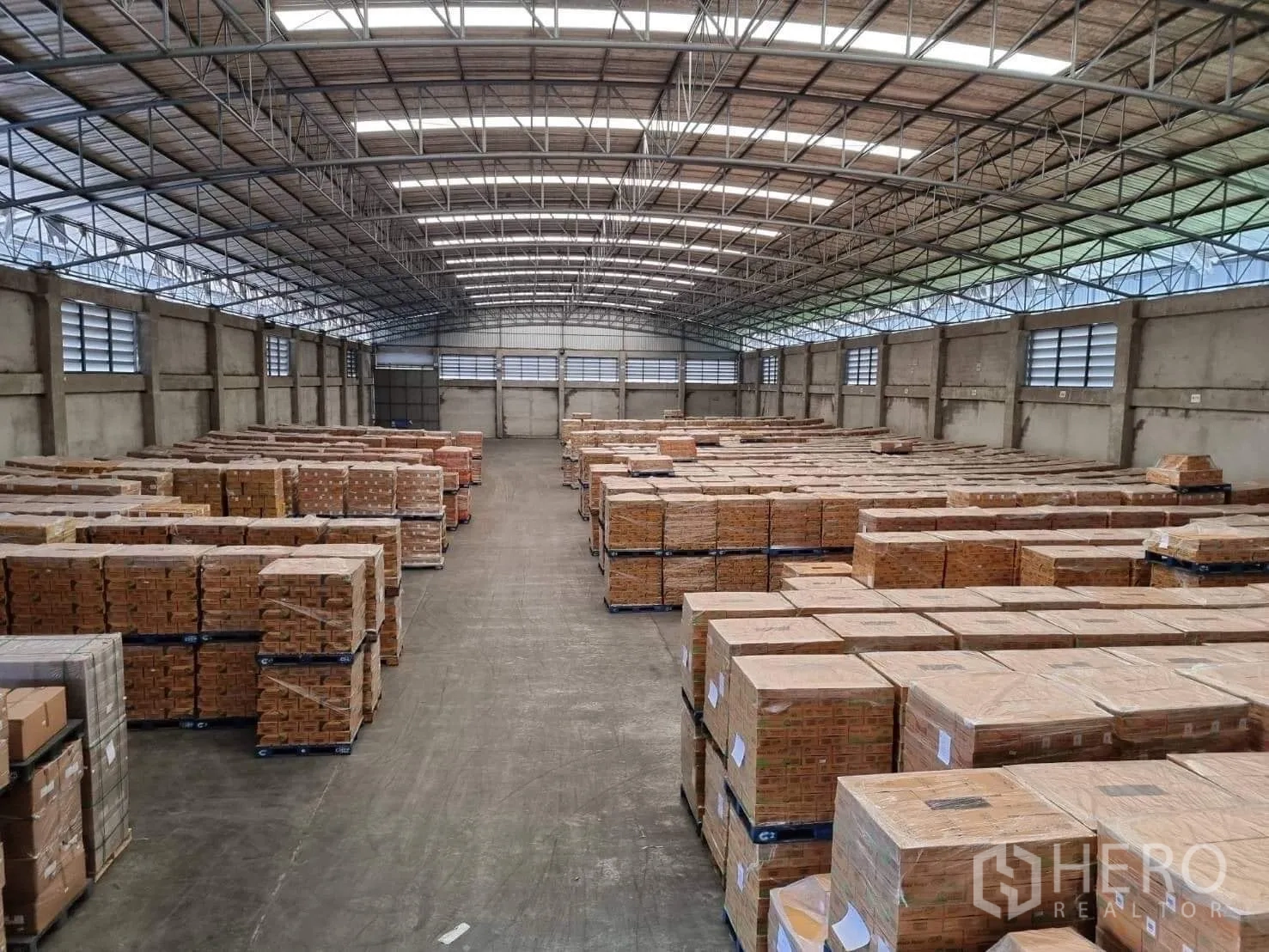 Factory for rent or sale in Pathum Thani - Wide warehouse aisle flanked by palletized goods under a high roof.