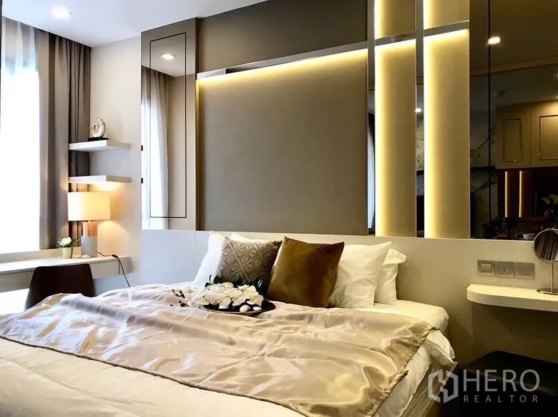 Condominium for rent in Watthana, Bangkok - Bedroom close-up with padded headboard, shelves, and a built-in desk by the window.