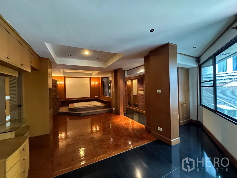 Townhouse for rent in Khlong Toei, Bangkok - Master bedroom with raised platform bed area, built-in storage and wide windows.