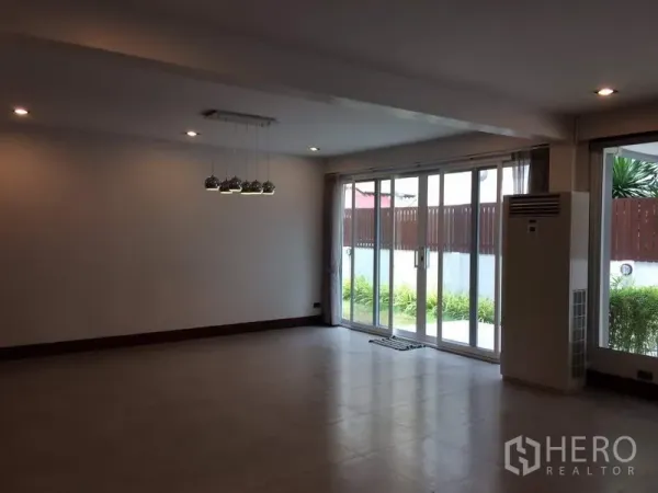 Detached House for rent or sale in Khan Na Yao, Bangkok - Spacious living room with sliding glass doors opening to a small garden
