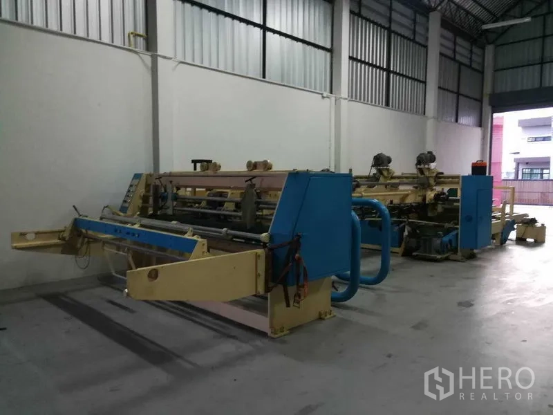 Factory for sale in Bang Len, Nakhon Pathom - Spacious high-ceiling production hall with industrial machinery inside the factory.