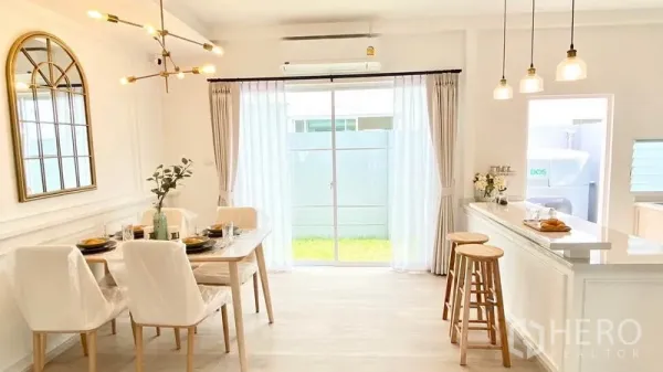 Townhouse for rent in Prawet, Bangkok - Dining area beside large sliding glass door to a small lawn, pendant lighting and a breakfast bar with stools.
