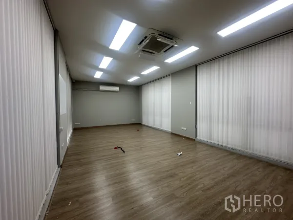 Home Office for rent in Pathum Wan, Bangkok - Open-plan office room with wood flooring, LED strip lights and vertical blinds along the windows.