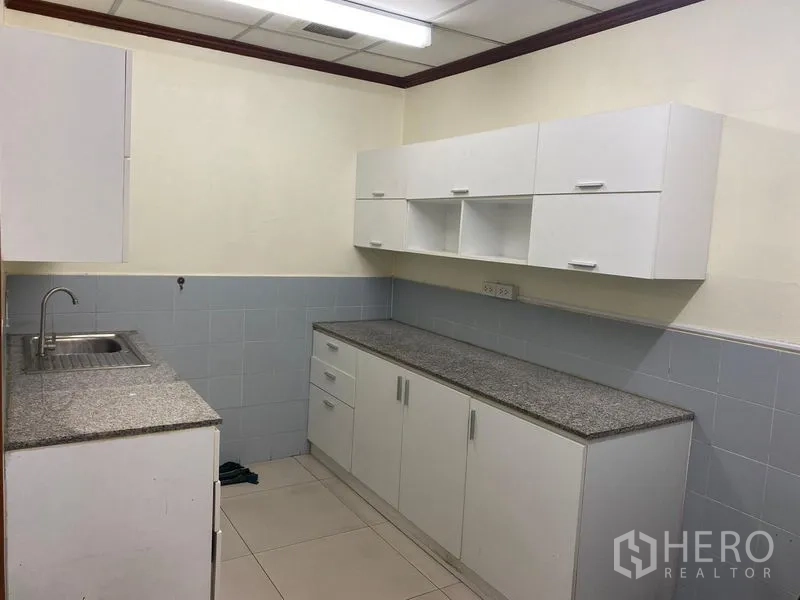 Office Space for rent in Huai Khwang, Bangkok - Pantry kitchenette with sink, granite-style countertops and white cabinetry.