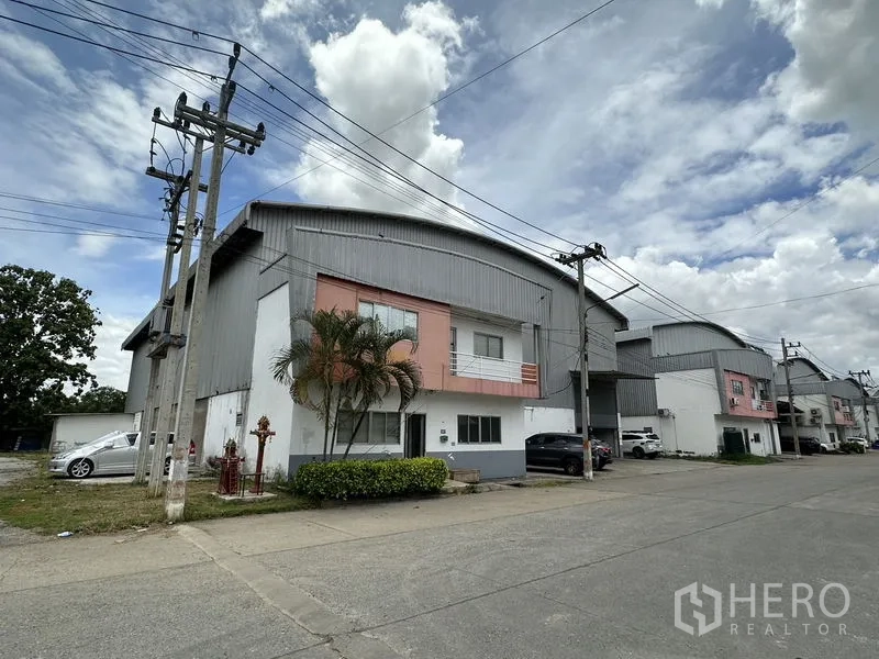 Factory for rent in Phra Nakhon Si Ayutthaya - Corner perspective of the industrial row with palm landscaping beside the factory and power lines.