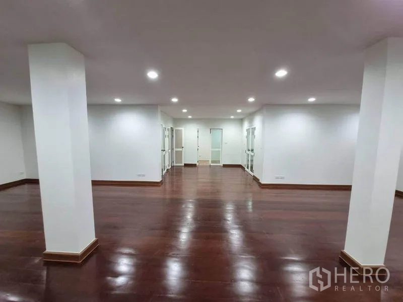 Shophouse for rent in Bang Rak, Bangkok - Open commercial floor with wood flooring, ceiling spotlights, pillars and multiple glass doors for flexible layout.