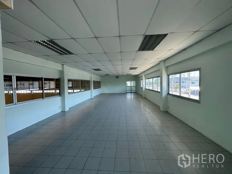Factory for rent in Chon Buri - Long open-plan office area with tiled floors and rows of windows providing natural light.