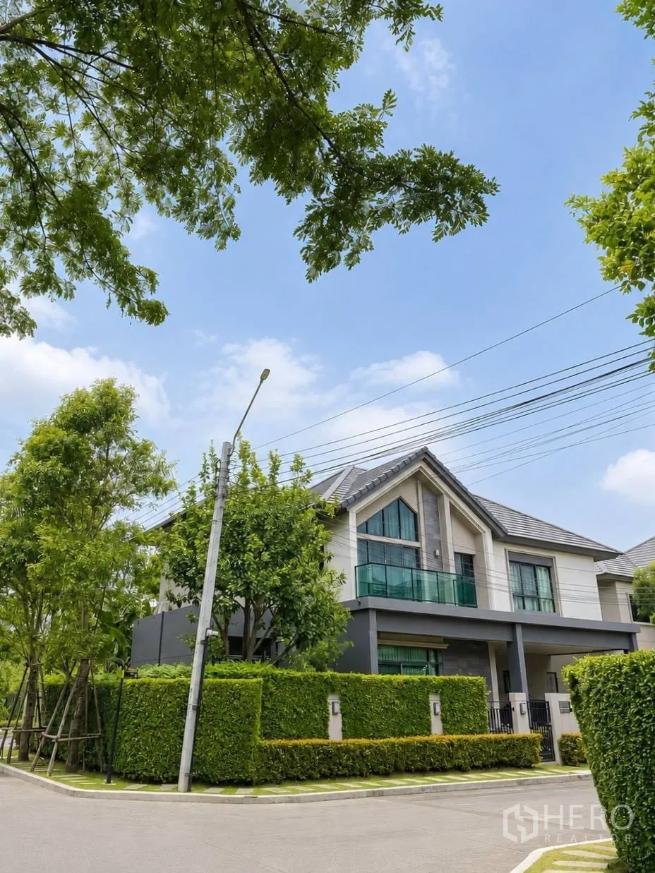 Detached House for sale in Bang Kruai, Nonthaburi - Street view of a contemporary detached house behind trimmed hedges.