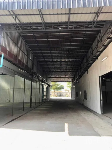 货栈 出租在Pathum Thani - 高挑雨棚装卸走廊，钢桁架与侧面卷帘门通向院内。