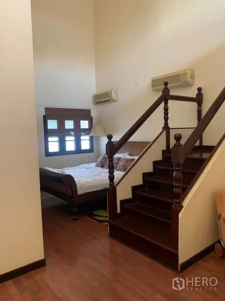Townhouse for rent or sale in Phra Khanong, Bangkok - Split-level bedroom with short wooden staircase, timber floors and air conditioning.