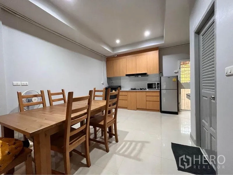 Townhouse for rent in Khlong Toei, Bangkok - Dining area with wooden table and chairs adjoining an open kitchen.