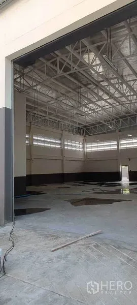 Warehouse for rent in Bang Khun Thian, Bangkok - View through the large roller door to the bright, ventilated warehouse hall with tall roof.