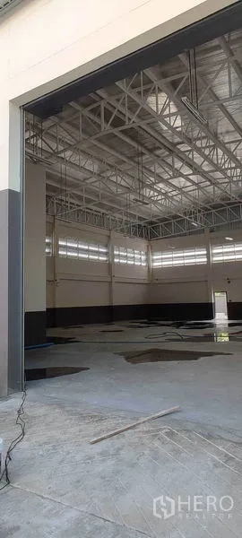 Warehouse for rent in Bang Khun Thian, Bangkok - View through the large roller door to the bright, ventilated warehouse hall with tall roof.
