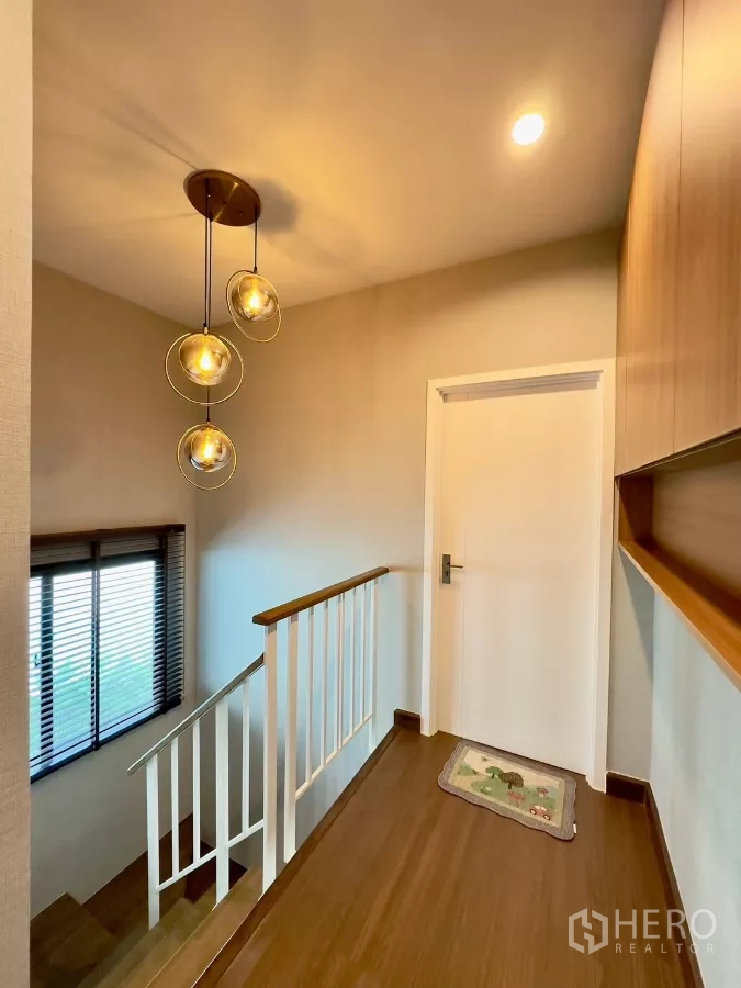 Detached House for rent in Samut Prakan - Stair landing with modern pendant lights, window and wood flooring.