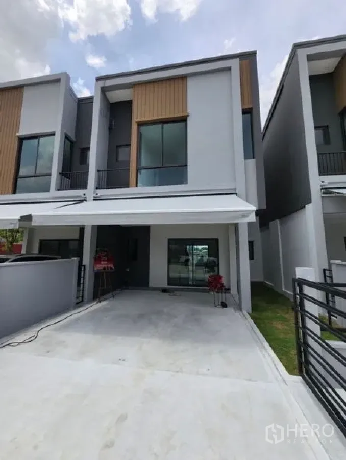 联排别墅 出租在Bang Phli, Samut Prakan - 当代风两层联排别墅外立面，带有顶棚车位与玻璃入户门。