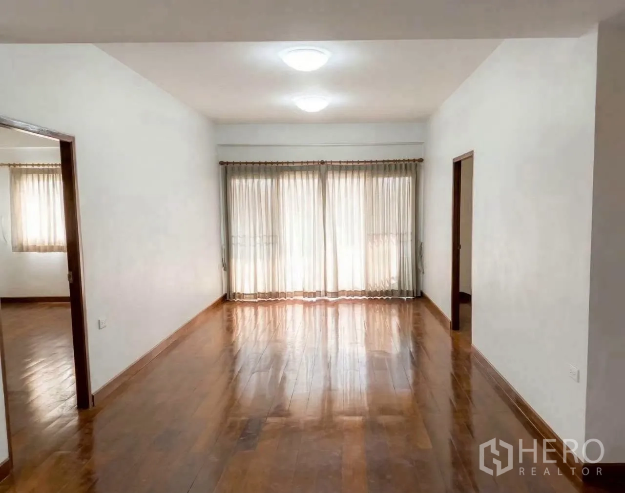 Factory for rent in Phra Samut Chedi, Samut Prakan - Upper-floor room with polished wooden flooring, white walls, and curtained windows.