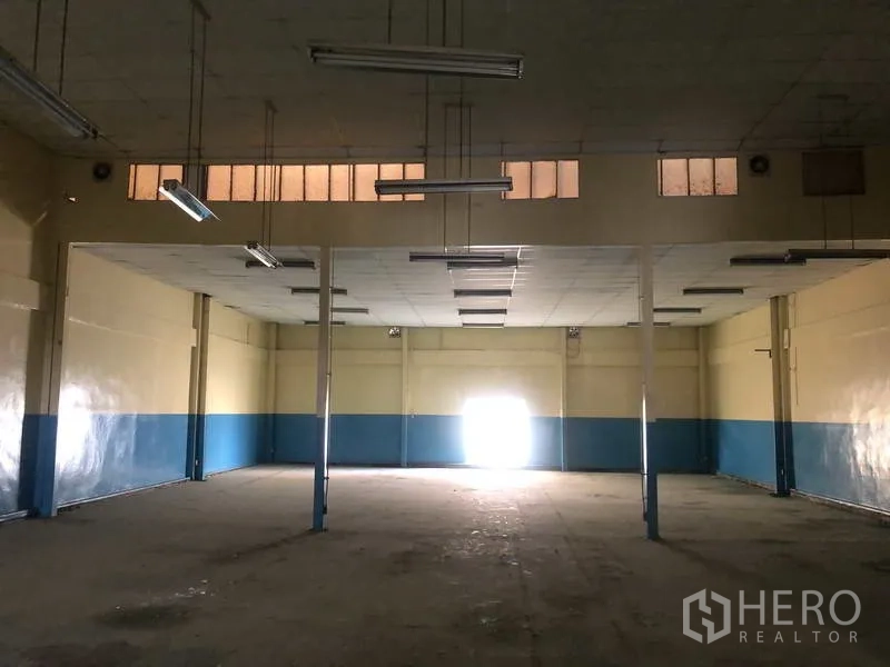 Factory for rent in Khlong Luang, Pathum Thani - Wide factory hall with hanging lights, upper clerestory windows and open floor space.