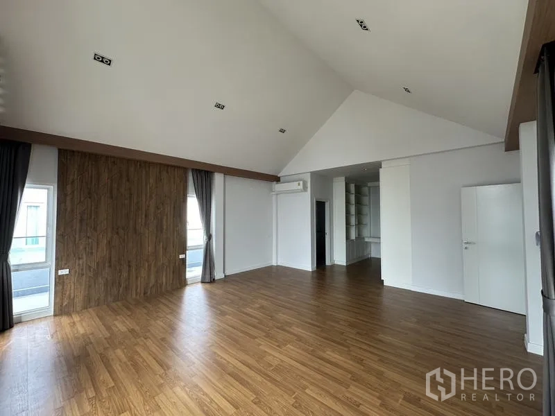 Detached House for sale in Lam Luk Ka, Pathum Thani - Expansive master bedroom with high vaulted ceiling and wood floor.