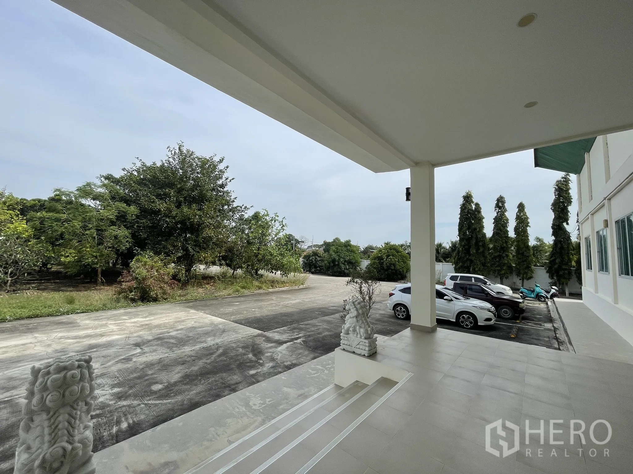 Warehouse for sale in Lat Lum Kaeo, Pathum Thani - Covered front porch with steps overlooking parking bays and landscaped trees.