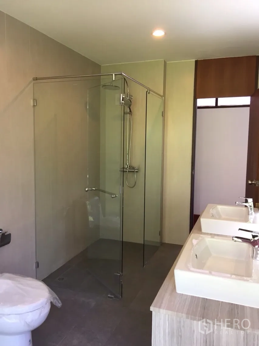 Detached House for rent in Sathon, Bangkok - Contemporary bathroom with glass shower enclosure, dual sinks and toilet.
