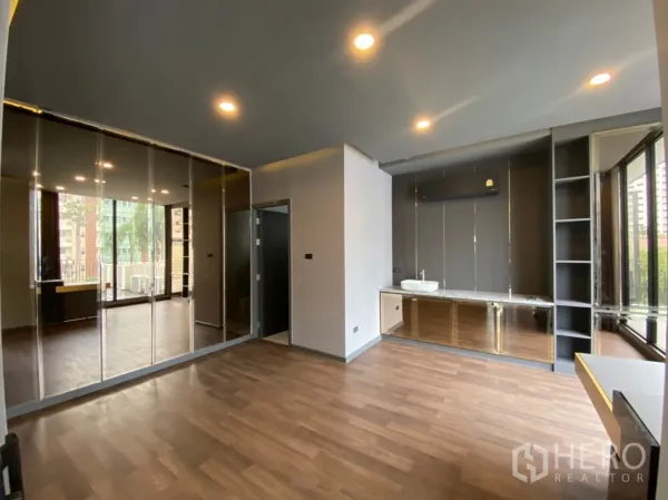 Home Office for rent or sale in Watthana, Bangkok - Modern home office room with wood floors, mirrored cabinets, built‑in counter with sink, and large windows.