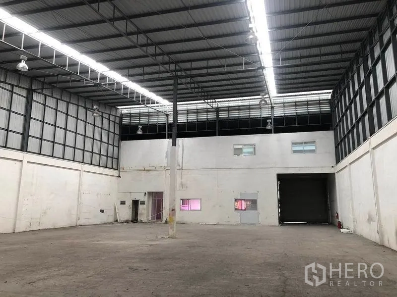 工厂 出租在Pak Kret, Nonthaburi - 宽阔厂房地面，明亮长条照明与大型卷帘门便于卡车进出。