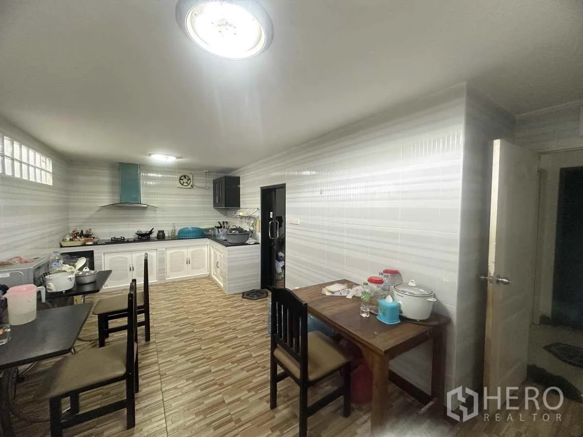 Detached House for sale in Pathum Thani - Kitchen alternate view with countertops, cabinets and two dining tables.