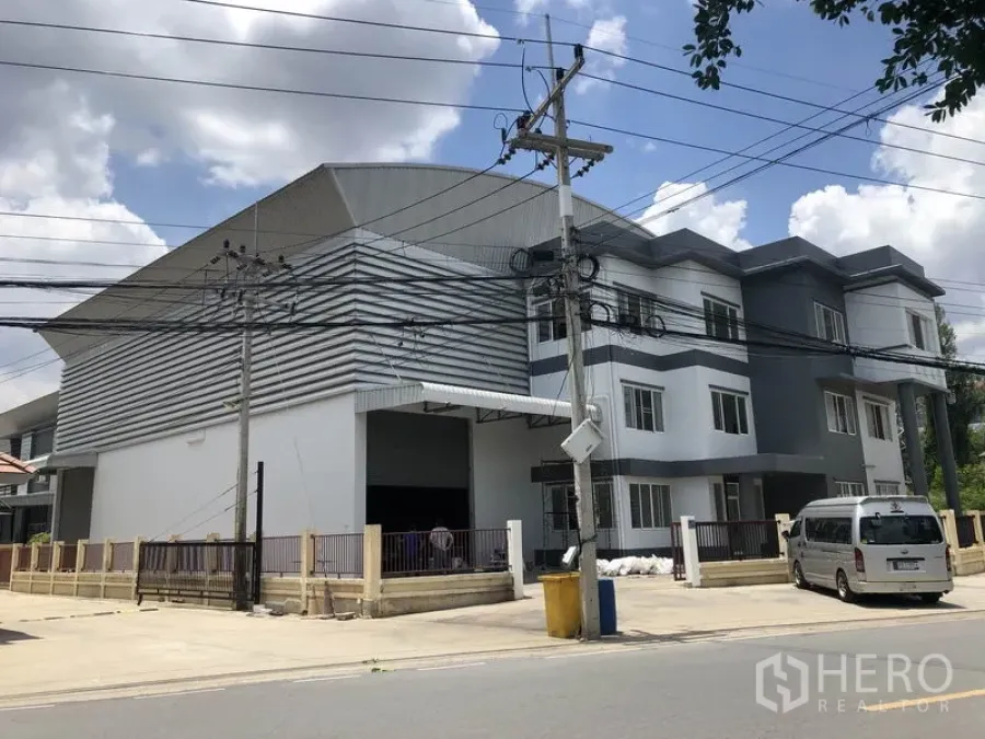 Warehouse for rent or sale in Lam Luk Ka, Pathum Thani - Street view of a modern warehouse with a three-storey office block, gated driveway and loading bay in Lam Luk Ka.