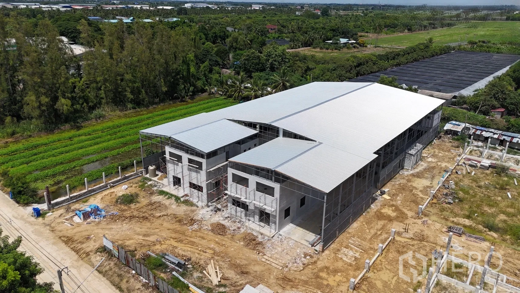 โรงงาน for rent in Phutthamonthon, Nakhon Pathom - ภาพมุมสูงของอาคารโรงงานหลังคาจั่วคู่ รายล้อมด้วยพื้นที่สีเขียว