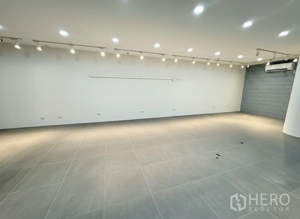 Retail Space for rent - Large showroom space with spotlight tracks, tiled floors, and wall-mounted air conditioning ready for fit-out.