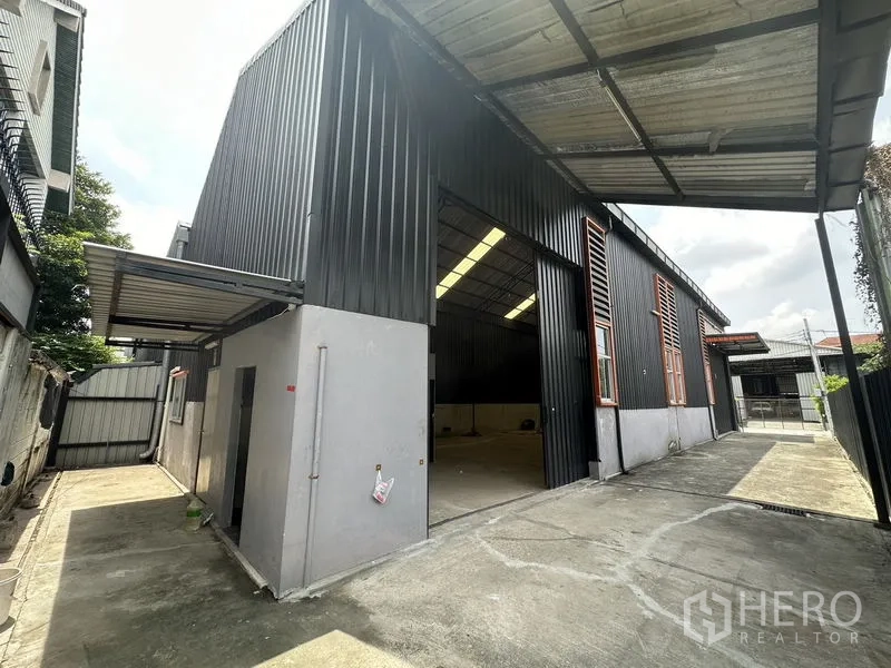Warehouse for rent in Lat Phrao, Bangkok - Main warehouse entrance with tall sliding door, sheltered loading bay and concrete yard.
