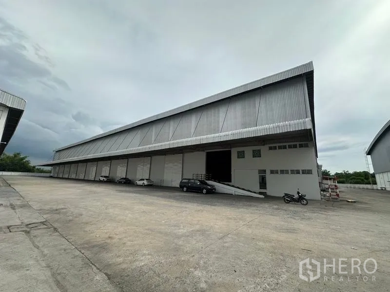 Warehouse for rent in Phra Nakhon Si Ayutthaya - Wide view of warehouse facade and truck yard with loading docks and ramp.