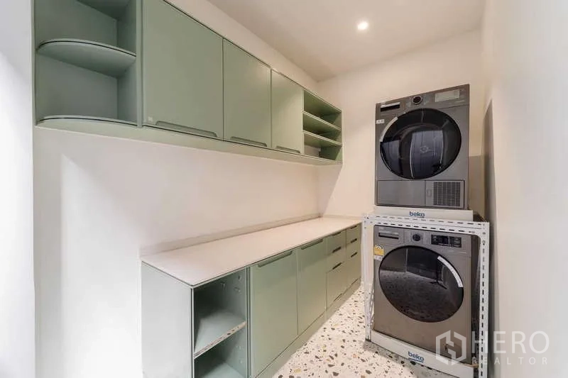Townhouse for rent or sale in Watthana, Bangkok - Laundry room with green cabinetry and stacked washer and dryer.