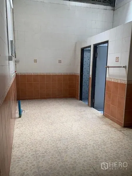 Shophouse for rent in Khlong Toei, Bangkok - Tiled utility area with brown and white wall tiles, two doorways and a plumbing point.